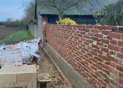 A partially constructed brick wall with visible cement blocks at the base