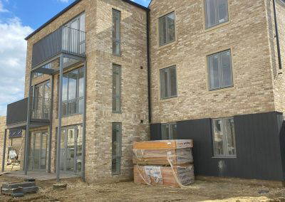 Newly built brick structure with large glass windows and balcony