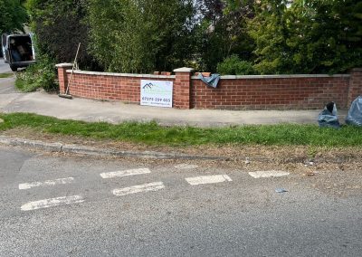A newly built brick boundary wall with a clean finish and a company sign displayed