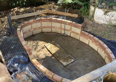 Partially built brick pond structure with a smooth concrete base